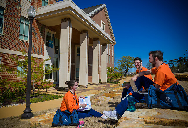Three students having fun studying outside the Nursing building.
