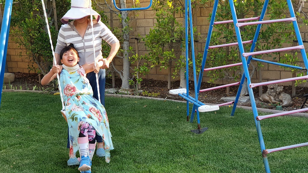 A girl named Jojo who is receiving gene therapy enjoys time outdoors on a swing with her mother.