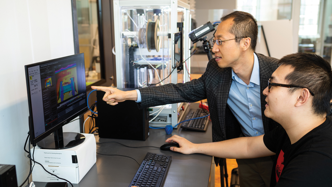 Peter Liu and colleague view computer screen in laboratory